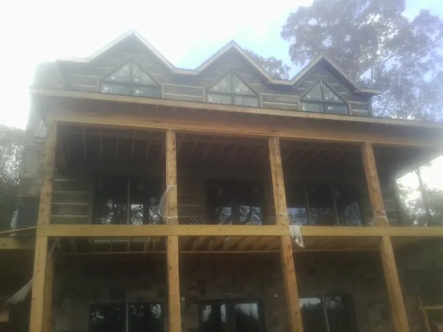 Dormers and porch framing on a large log home under construction — Roof Coating work by our crew in Winterville