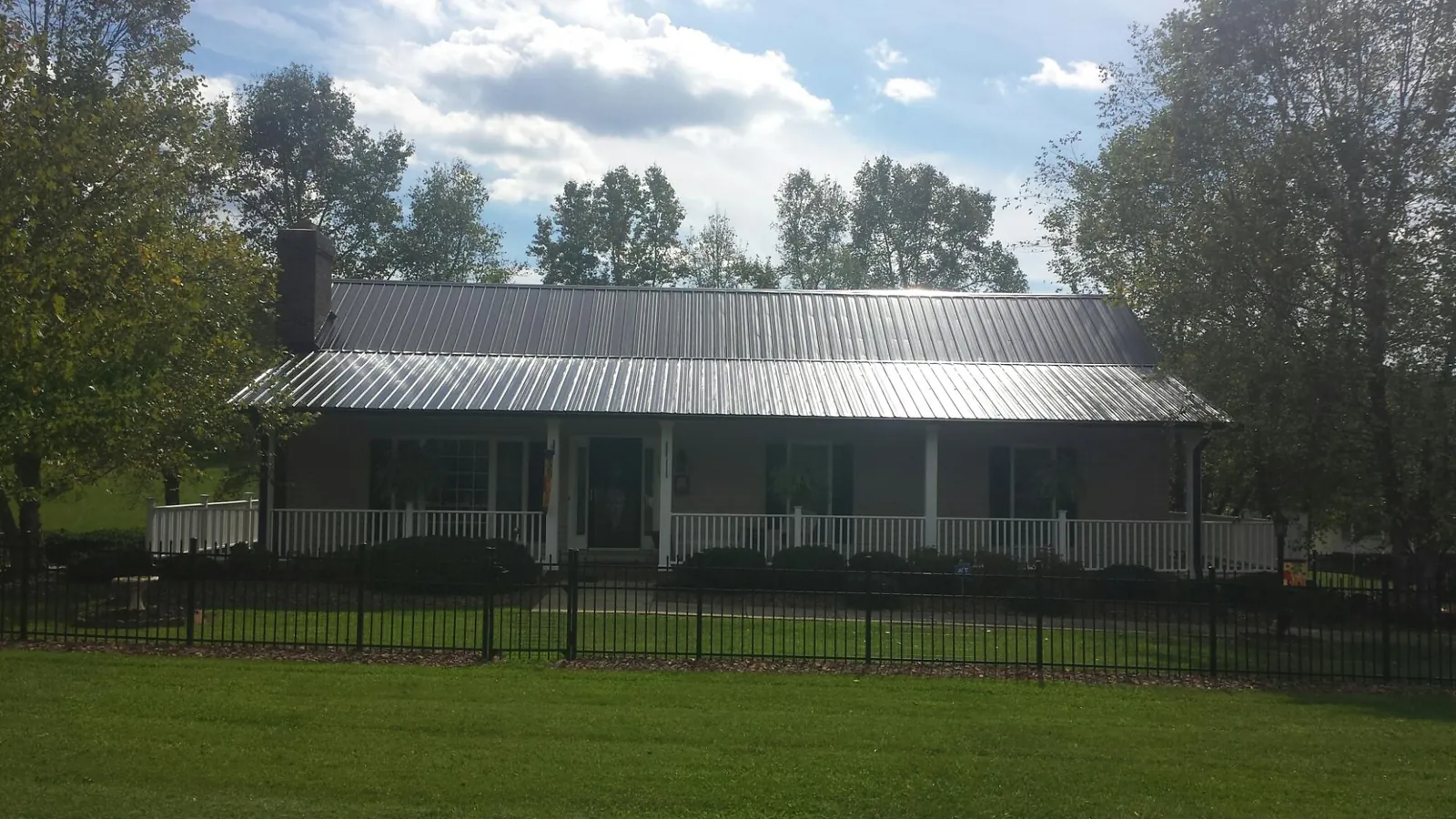 Gray metal roof on a brick ranch with a full width front porch — Gutter Guard Installation work by our crew in Winterville